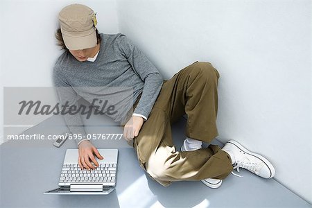 Young man sitting on the ground, using laptop computer, high angle view