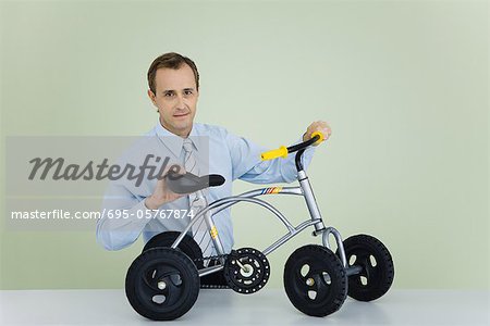 Man holding child's bicycle, looking at camera