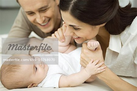 New parents smiling at infant, mother holding baby's legs, close-up
