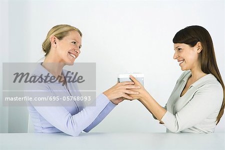 Two women face to face, exchanging gift, smiling at each other