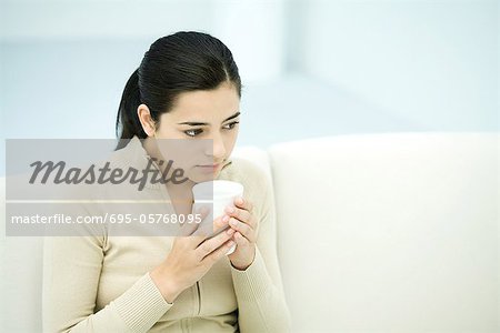 Junge Frau sitzend, halten Kaffeetasse, Wegsehen