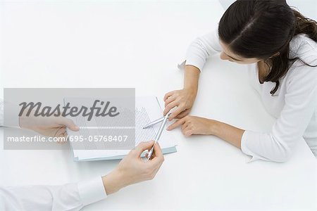 Man holding document, woman carefully reading it, high angle view