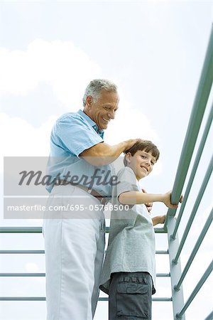 Alter Mann mit Enkel auf Balkon, seine Hand auf dem Kopf, beide Lächeln