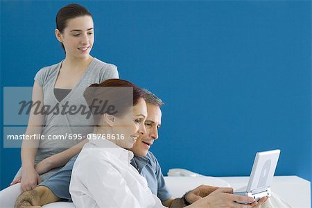 Family sitting on couch, watching portable DVD player together
