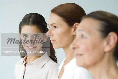 Three generations of women, focus on teen girl smiling at camera