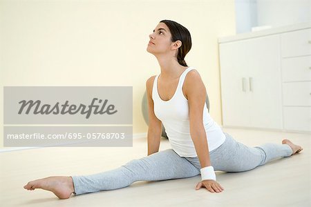 Young woman doing splits, looking up