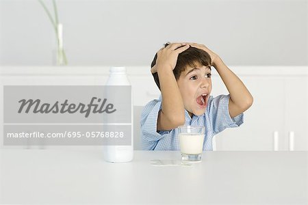 Boy with spilled milk, shouting, hands on head