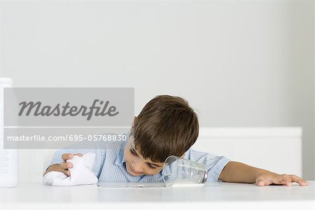 Boy wiping up spilled milk with towel