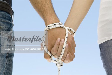 Couple's hands bound together with rope, close-up