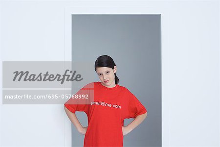 Preteen girl wearing tee-shirt printed with e-mail address, hands on hips, looking at camera