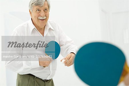 Senior man playing table tennis, smiling