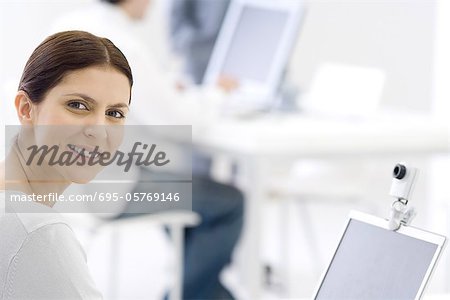 Femme au bureau, souriant par-dessus l'épaule à la caméra