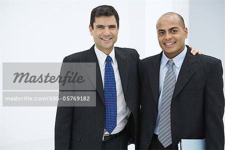 Two businessman, one with arm around the other's shoulder, smiling at camera