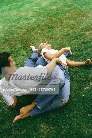 Couple s'allongeant sur la terre ensemble, rire, vue grand angle