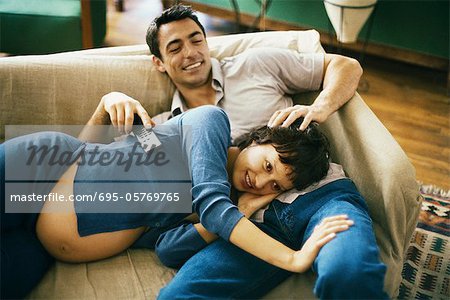 S'attendant à couple de détente sur le canapé, regarder la télévision, la femme se reposer la tête sur les genoux de l'homme