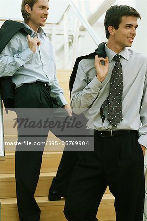 Les hommes d'affaires debout sur des marches, des vestes de costume par-dessus l'épaule