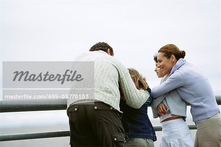 Family together at seaside, parents embracing children