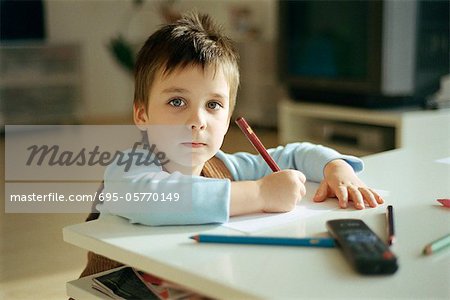 Little boy drawing, pausing to look at camera