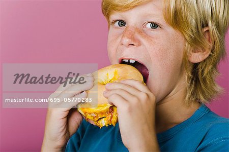 Garçon mangeant sandwich jambon et fromage