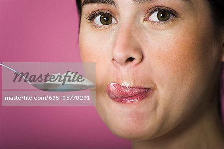 Femme avec une cuillère de crème glacée, se léchant les lèvres