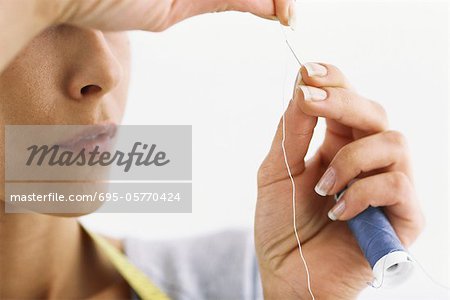 Woman threading needle, cropped