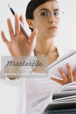 Woman with notepad, gesturing not to interrupt work