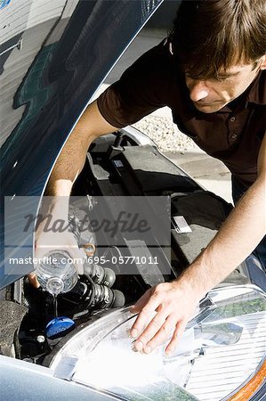 L'homme verse de l'eau dans le radiateur de voiture surchauffée