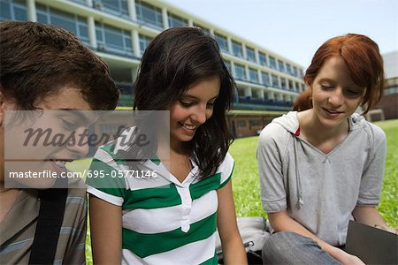 Teenager Freunden herumhängen, sitzen gemeinsam im Freien auf Rasen Schule