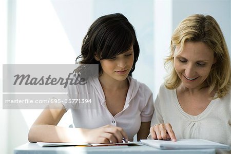 High school teacher and student reading notebook together
