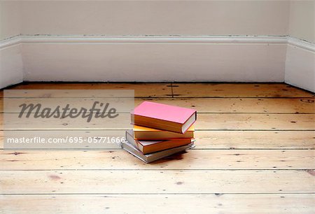 Books stacked on hardwood floor