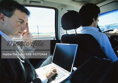 Businessman using laptop in taxi