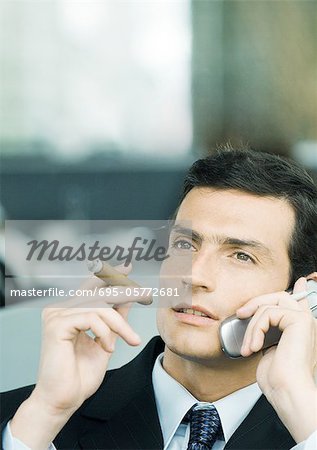 Geschäftsmann mit Handy und Zigarre rauchen