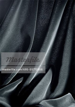 Folds in shiny black fabric, close-up, full frame