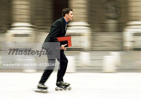 Businessman rollerblading in front of building, blurred.