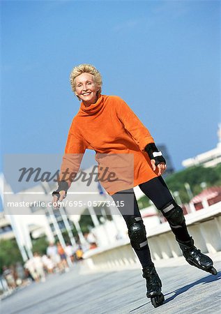 Mature woman in-line skating on boardwalk
