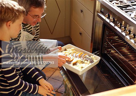 Man and child putting casserole in oven