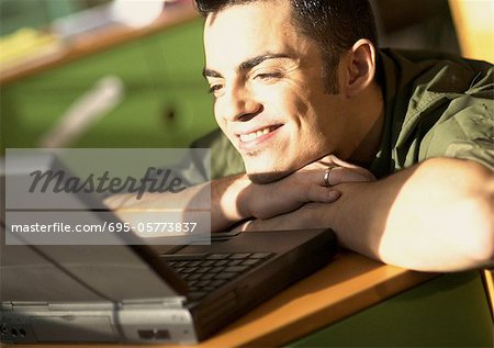 Man leaning on desk looking at laptop computer