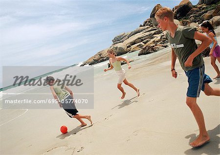 Jeunes jouant au soccer sur la plage