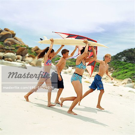 Adolescents et enfants en maillot de bain planche de surf et kite