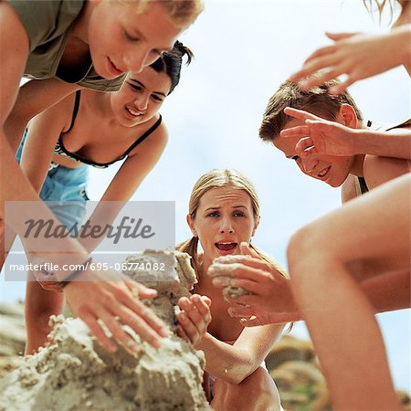 Young people making sandcastle, low angle view