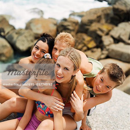 Young people at the beach leaning on each other