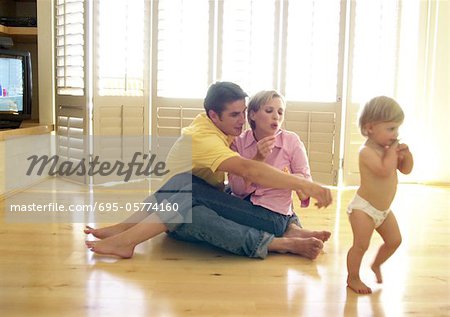 Couple assis sur le plancher, bébé walking away