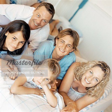 Parents and children lying on bed, smiling