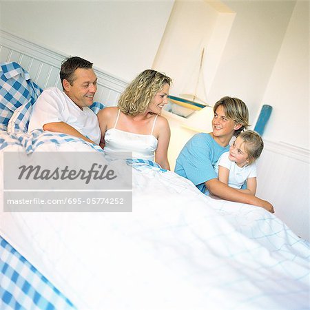 Parents and children on bed, smiling