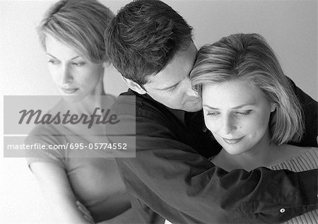 Femme debout derrière le couple s'enlaçant, b&w