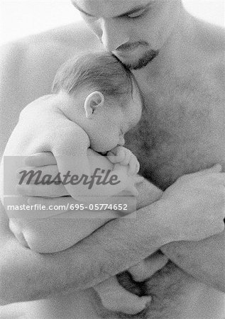 Father holding sleeping infant against bare chest, b&w