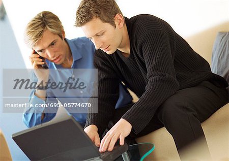 Zwei Männer, ein Telefon mit einem Laptop benutzen,