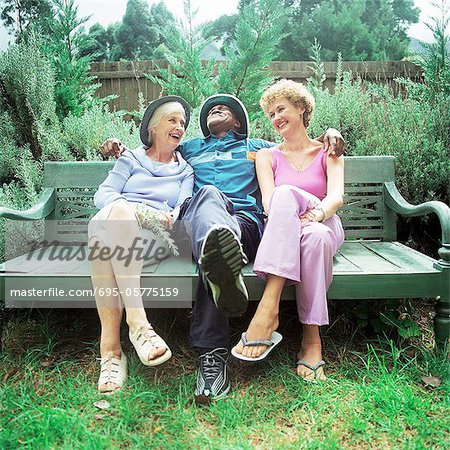 Älterer Mann zwischen zwei Frauen auf Bank sitzend