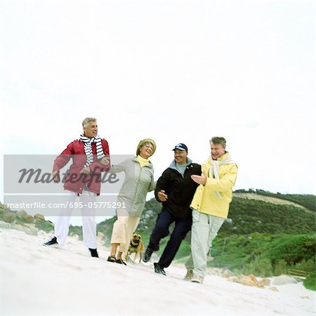 Mature group of friends arm in arm on beach, portrait