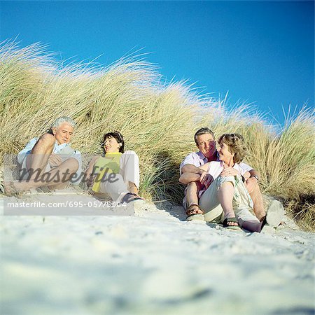 Two mature couples sitting on beach